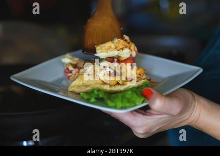 Frau legt ein Omelett aus einer Pfanne auf einen Teller. Hausgemachtes Frühstück Stockfoto