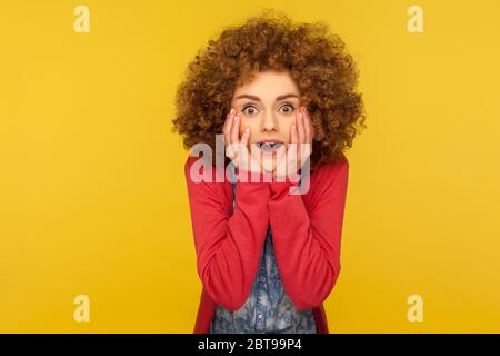 Oh mein gott, wow! Porträt von aufgeregt erstaunt Frau mit flauschigen lockigen Haar hält die Hände auf dem Gesicht und mit dem Mund offen in Überraschung, schockiert auszudrücken Stockfoto