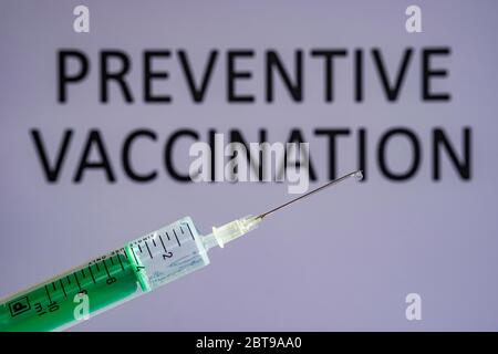 Diese Abbildung zeigt eine Einweg-Spritze mit hypodermischer Nadel, PRÄVENTIVE IMPFUNG auf einer grauen Tafel dahinter geschrieben Stockfoto