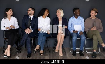 Glücklich verschiedene Geschäftsleute sitzen in Reihe, warten auf Interview Stockfoto