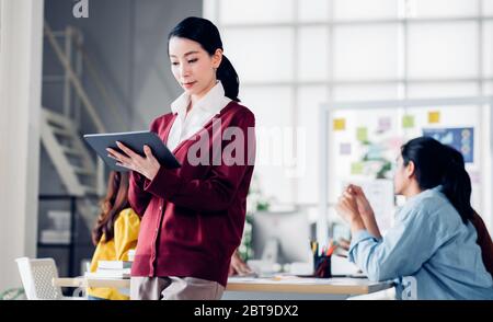 der asiatische Creative Director nutzt die Planung von Tablets, während ux-Entwickler und ui-Designer in Meet über das Design der Benutzeroberfläche für mobile Apps auf dem Whiteboard brainstorming Stockfoto