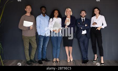Lächelnd verschiedene Geschäftsleute stehen in Reihe auf schwarzem Hintergrund Stockfoto