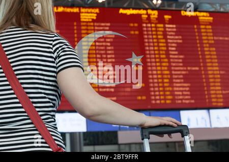 Frau schaut sich die Anzeigetafel am Flughafen an. Wählen Sie ein Land Türkei für Reise oder Migration. Stockfoto