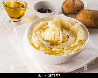 Kartoffelpüree in weiße Schüssel mit einem Tuch Serviette, Pfeffer und Olivenöl auf strukturierte konkrete weißer Hintergrund Stockfoto