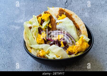 Taco Cig Kofte im türkischen mexikanischen Stil mit Kidney Beans, roten Zwiebeln, geriebenem Cheddar-Käse und Granatapfelsauce. Traditionelles Fast Food. Stockfoto