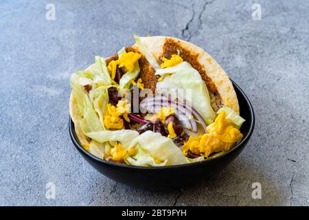 Taco Cig Kofte im türkischen mexikanischen Stil mit Kidney Beans, roten Zwiebeln, geriebenem Cheddar-Käse und Granatapfelsauce. Traditionelles Fast Food. Stockfoto