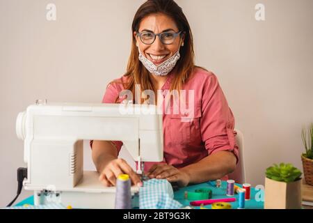 Frau Arbeiter mit Nähmaschine während der Herstellung Gesicht medizinische Masken während Coronavirus Ausbruch - Home Made diy Schutzmaske gegen Virus Stockfoto