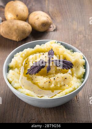 Kartoffelpüree mit frischen roten Basilikum in blauer Schüssel auf Holz- Hintergrund. Kopieren Sie Platz. Stockfoto