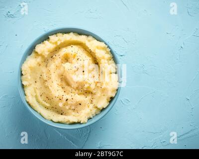 Kartoffelpüree mit Paprika in blauer Schüssel auf Blau konkreten Hintergrund. Top View oder flach. Kopieren Sie Platz. Stockfoto