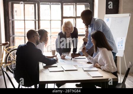 Diverse Mitarbeiter, die bei Meetings mit Projektdokumenten arbeiten Stockfoto