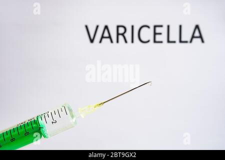 Diese Abbildung zeigt eine Einweg-Spritze mit hypodermischer Nadel, VARICELLA auf einer weißen Tafel dahinter geschrieben Stockfoto