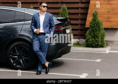 Eleganter Mann im Anzug, der neben dem Auto steht Stockfoto