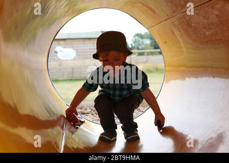 Bezaubernder kleiner Junge, 1 - 2 Jahre alt, spielt in einer Pfeife, Manor Farm Country Park, Hampshire, England, Großbritannien. MODELL FREIGEGEBEN Stockfoto