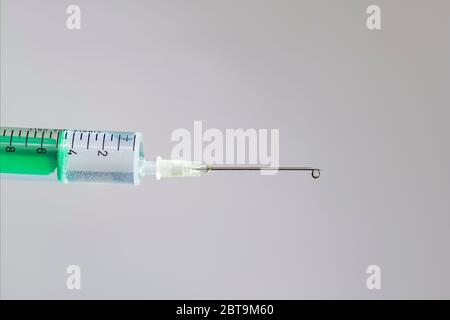 Diese Abbildung zeigt eine Einwegspritze mit hypodermischer Nadel, dahinter eine weiße Tafel Stockfoto