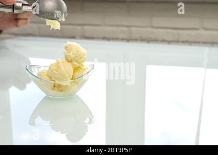 Eine Kugel Eis wird in eine Glasschüssel, Platz für Text gelegt Stockfoto