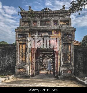 Frau, die durch einen alten Bogen am Imperial Minh Mang Grab in Hue, Vietnam, Imperial City Stockfoto