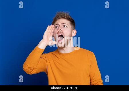 Attraktiver junger Mann mit gelbem T-Shirt auf blauem Hintergrund Stockfoto