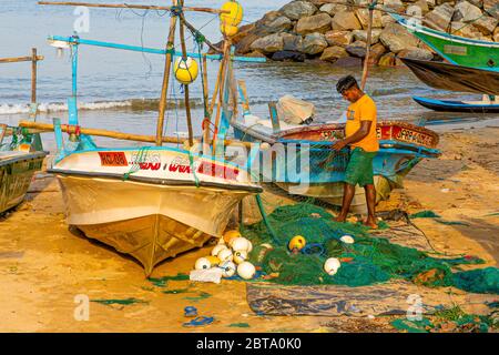 Fischer pflegen ihre Netze mit ihren Booten am Strand außerhalb von Galle Stockfoto