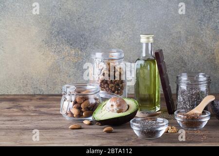 Gesunde Fette Quellen Flachs Nüsse Öl Avocado Chia Samen und Bitter Schokolade auf dunklem Hintergrund.gesunde Ernährung umweltfreundliche Konzept, kopieren Raum Stockfoto