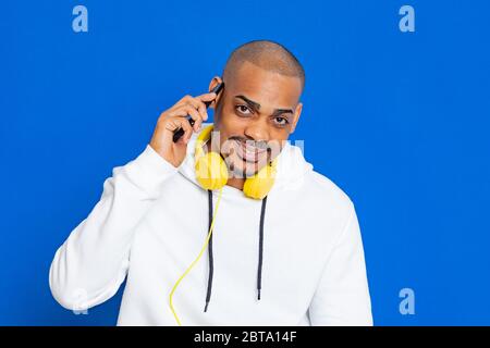 Afrikaner trägt ein weißes Sweatshirt auf blauem Hintergrund Stockfoto
