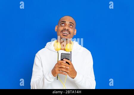 Afrikaner trägt ein weißes Sweatshirt auf blauem Hintergrund Stockfoto