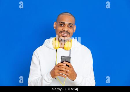 Afrikaner trägt ein weißes Sweatshirt auf blauem Hintergrund Stockfoto