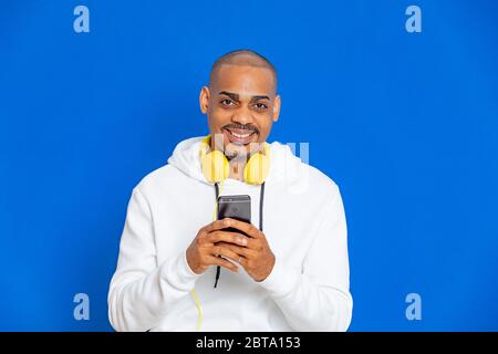 Afrikaner trägt ein weißes Sweatshirt auf blauem Hintergrund Stockfoto
