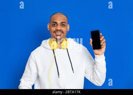 Afrikaner trägt ein weißes Sweatshirt auf blauem Hintergrund Stockfoto