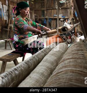 Lung Tam, Vietnam - 9. Januar 2020 - Frau, die auf traditionelle Weise webt, konzentriert sich auf lin und Webstuhl Stockfoto