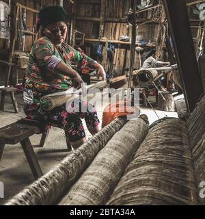 Lung Tam, Vietnam - 9. Januar 2020 - Frau, die auf traditionelle Weise webt, konzentriert sich auf lin und Webstuhl Stockfoto