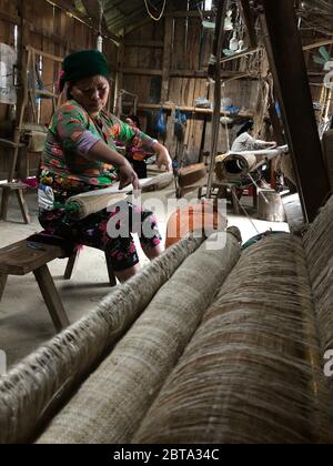 Lung Tam, Vietnam - 9. Januar 2020 - Frau, die auf traditionelle Weise webt, konzentriert sich auf lin und Webstuhl Stockfoto