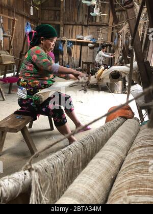 Lung Tam, Vietnam - 9. Januar 2020 - Frau, die auf traditionelle Weise webt, konzentriert sich auf lin und Webstuhl Stockfoto