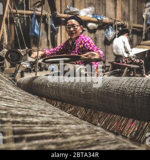 Lung Tam, Vietnam - 9. Januar 2020 - Frau, die auf traditionelle Weise webt, konzentriert sich auf lin und Webstuhl Stockfoto