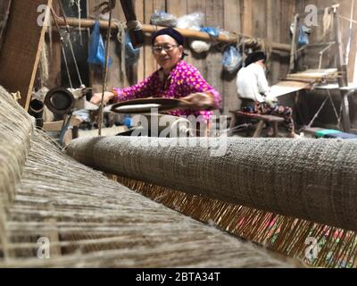 Lung Tam, Vietnam - 9. Januar 2020 - Frau, die auf traditionelle Weise webt, konzentriert sich auf lin und Webstuhl Stockfoto