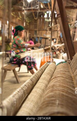 Lung Tam, Vietnam - 9. Januar 2020 - Frau, die auf traditionelle Weise webt, konzentriert sich auf lin und Webstuhl Stockfoto