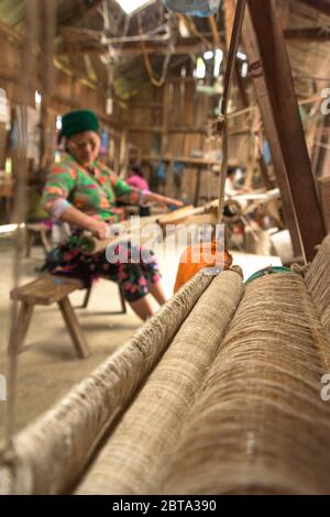 Lung Tam, Vietnam - 9. Januar 2020 - Frau, die auf traditionelle Weise webt, konzentriert sich auf lin und Webstuhl Stockfoto