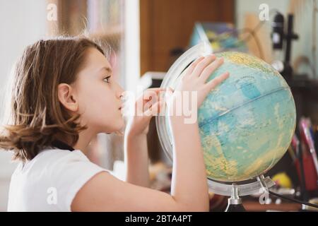 Junges Mädchen siiting an ihrem Schreibtisch und beobachten einen Globus.. Stockfoto