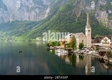 Panoramalicht auf das Bergdorf Hallstatt, Salzkammergut, Österreich, mit 'Plätten', traditionellen hölzernen Flachbooten, die auf dem Wasser schwimmen Stockfoto