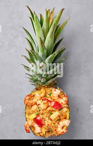 Thai Ananas gebratener Reis oder Kao Pad Sapparod in geschnittenen Ananasschüssel auf grauem Betongrund. Kao Pad Sapparod ist ein thailändisches Gericht. Thailand Stockfoto