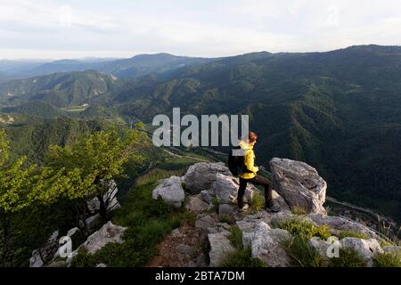 Frau auf dem Gipfel eines Berges, die aus der Perspektive betrachtet Stockfoto
