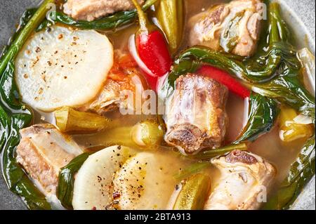 Sinigang na Baboy oder Filipino Schweinefleischsuppe aus nächster Nähe. Sinigang ist ein philippinisches Gericht mit Fleisch, Bamia, Daikon, Spinat, Fischsauce. Filipino Foo Stockfoto