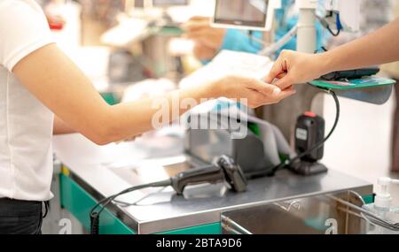 Weibliche Hand mit Münzgeld bezahlen für Warenkonzept. Hand geben Bargeld und Hand empfangen Bargeld, Zahltag bezahlen Kasse an der Kasse Zugang im Supermarkt. Stockfoto