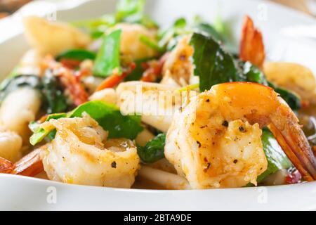 Nahaufnahme von würzigen frittierten Meeresfrüchten mit Garnelen in weißem Gericht. Stockfoto