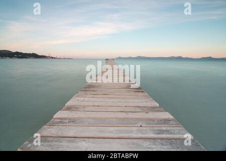 Bild von einem hölzernen Pier zum Meer, mit seidigem Wasser auf der Insel Mallorca. Lange Belichtungszeit Stockfoto