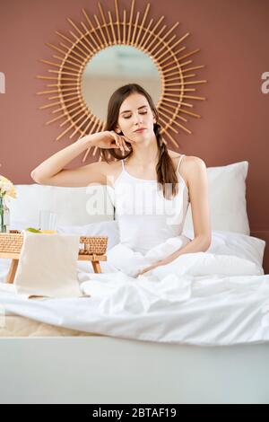 Verträumt und luftig-Fee sitzendes Mädchen auf dem Bett in hellen Morgenlicht Stockfoto