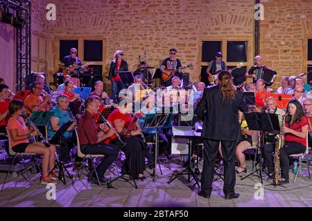 CHARNAY, FRANKREICH, 4. Juli 2019 : ein Amateurorchester spielt mit einer Rockband während der Probe auf dem Dorfplatz. Stockfoto