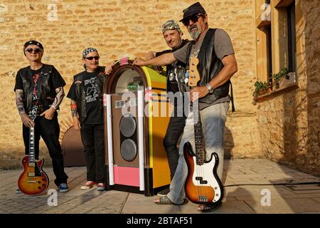 CHARNAY, FRANKREICH, 5. Juli 2019 : eine Amateurrock-Band posiert mit einer Juke-Box auf dem Dorfplatz. Stockfoto