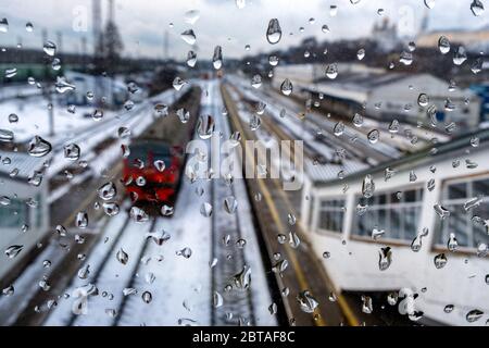 Regentropfen auf Fenster und Hintergrund ist ein Zug und Gleise. Nahaufnahme von Tropfen. Wladimir, Russland Stockfoto