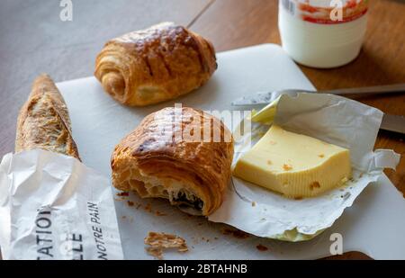 Französische Elemente zum großartigen Frühstück - Schokoladencroissants, Baguette in einer Tüte, frische Butter und Milch. Stockfoto