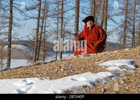 KHATGAL, MONGOLEI, 2. März 2020 : der junge mongolische Mann in traditioneller Kleidung posiert in einer Waldlandschaft. Stockfoto